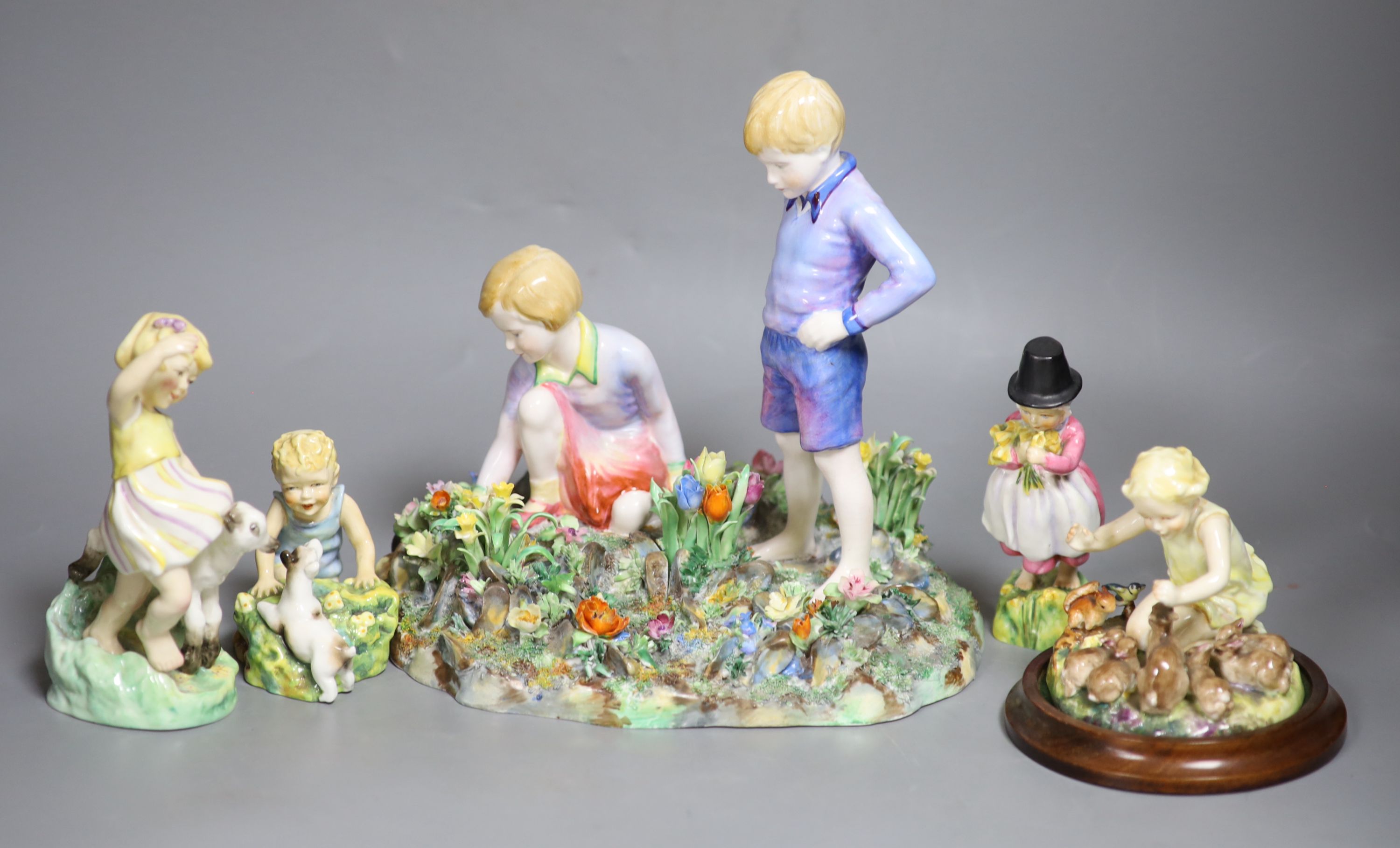 Four Royal Worcester figures of children by E.G. Doughty: 3150, 3076, 3103, 1416, and a larger Staffordshire table centre of a boy and